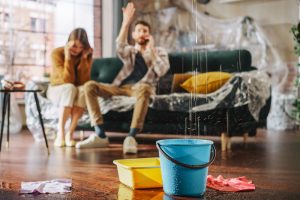 Family sitting on couch, upset, watching water leak from ceiling