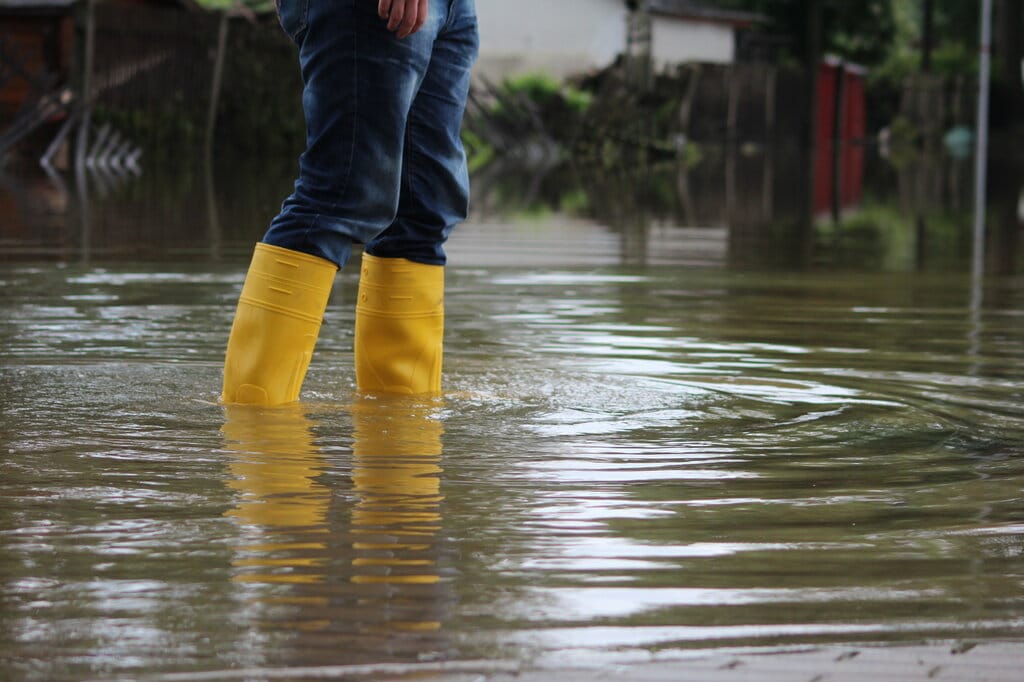 Person Wading Through Flood Water In Rubber Boots