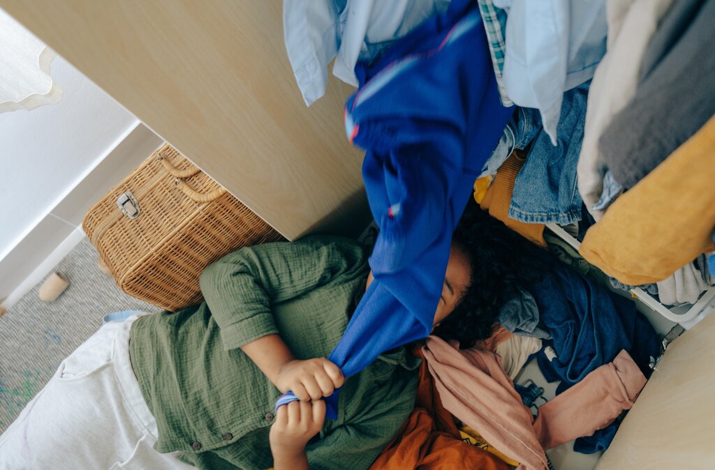 person lying on the floor of a crowded closet
