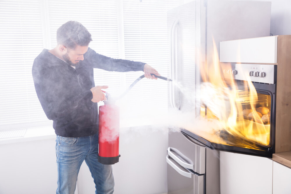 man attempting to extinguish a fire in the kitchen