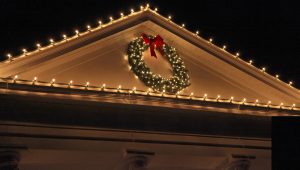 lighted holiday wreath on home exterior