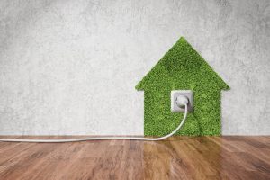 Eco-friendly electricity at home remodeling concept. Electric outlet on wall and grass in shape of house. Sustainable energy source concept, right composition.