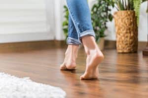 Young woman walking in the house on the warm floor. Gently walked the wooden panels. Article about how to extend the lifespan of hardwood floors