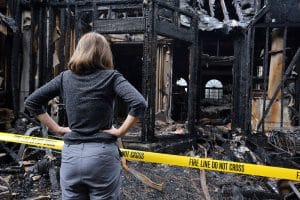 Woman standing outside her house after a fire, wondering if she save damaged items