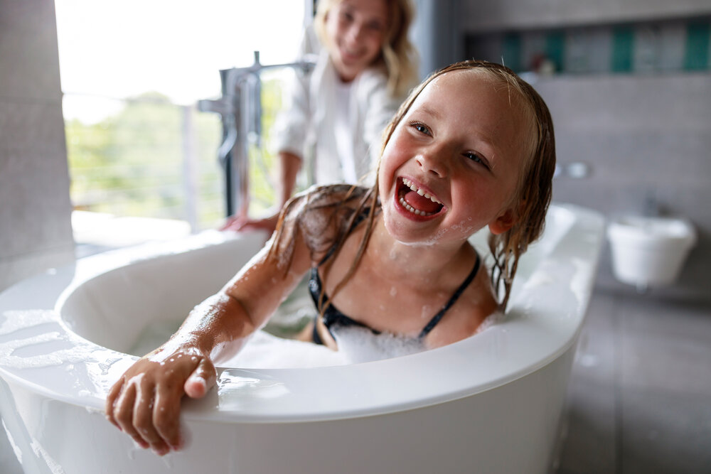 Smiling girl having fun in the bath with mom stock photo